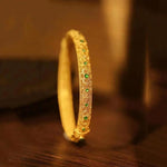 Armband im Stil eines Armreifs mit goldenen grünen Edelsteinen und floralen Mustern im ethnischen Stil