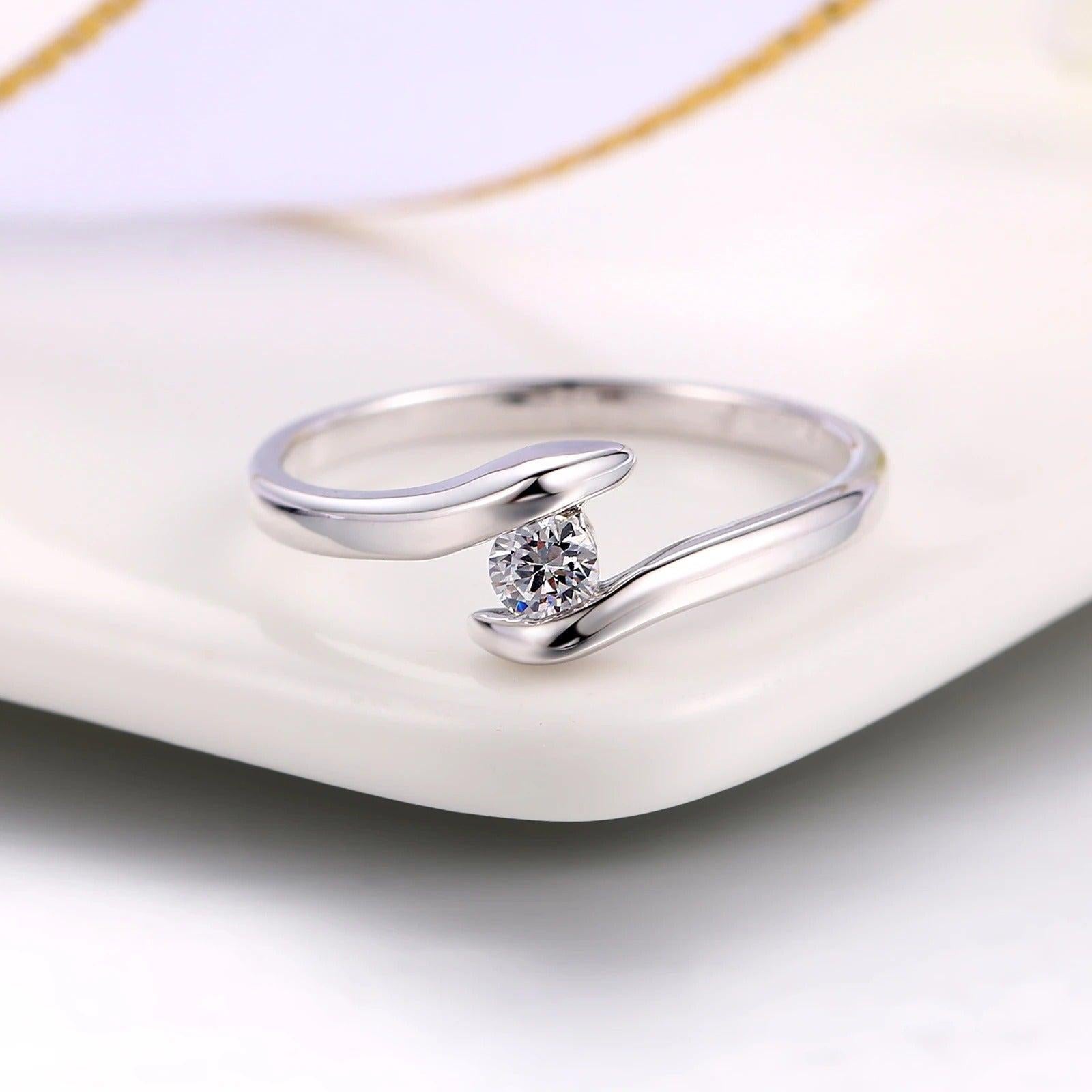 Ring mit gebogener Stange aus Silber und strahlendem Diamanten in der Mitte